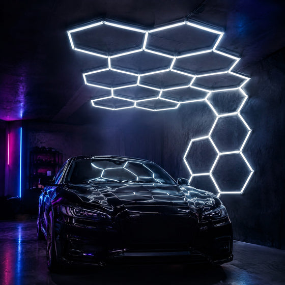 Éclairage LED hexagonal en nid d'abeille blanc au plafond et sur un mur d'un garage de detailing