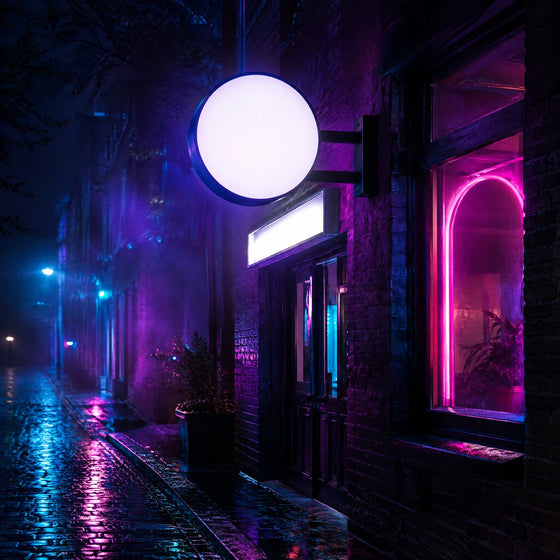 Enseignes lumineuses : enseigne drapeau ronde, caisson blanc et néon rose sur la façade d'une boutique la nuit