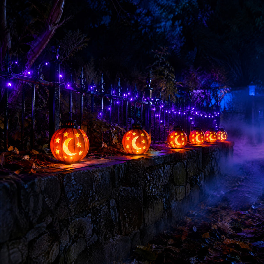 Halloween lumineux : lanternes citrouilles orange à motifs lune et étoile sur un muret, guirlande violette, brume