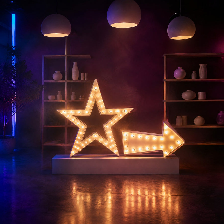 Lettres lumineuses : étoile et flèche à ampoules chaudes, style forain, sur un socle blanc dans une boutique concept