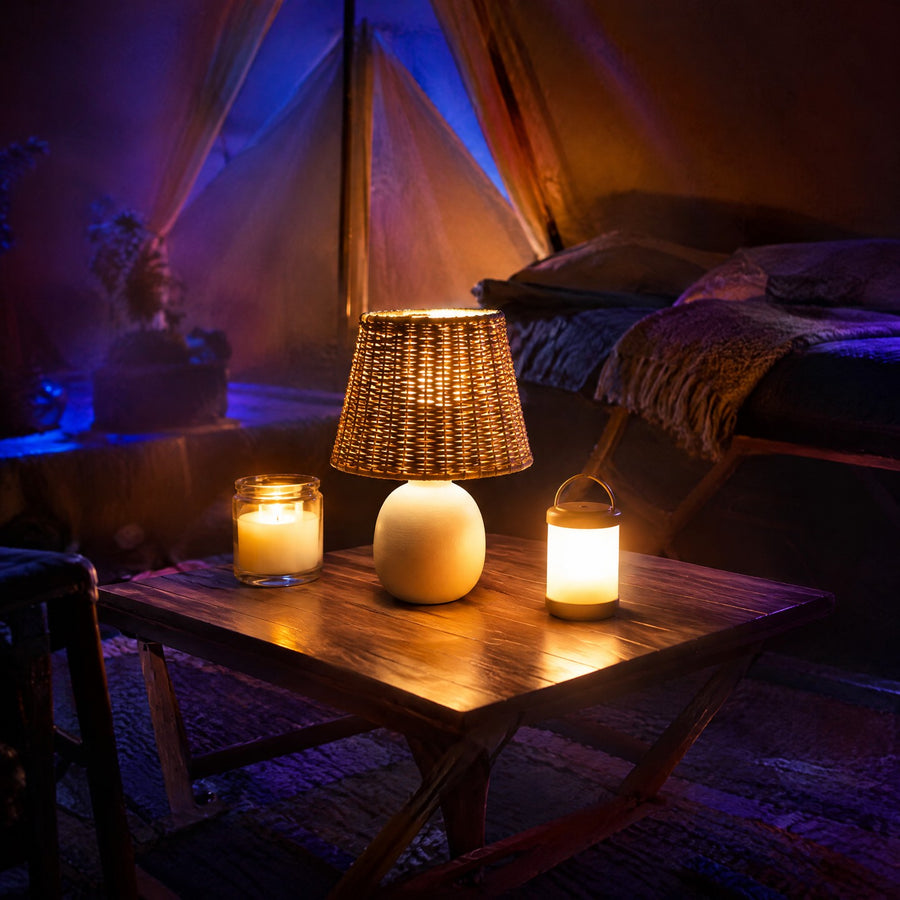Lumières sans fil sur batterie : lampe rechargeable, bougie LED et lanterne cylindrique sur une table dans une tente