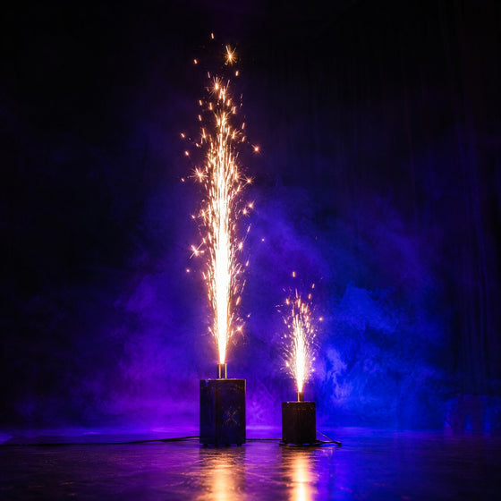 Machines à étincelles froides projetant deux gerbes dorées sur une scène sombre dans une brume violette
