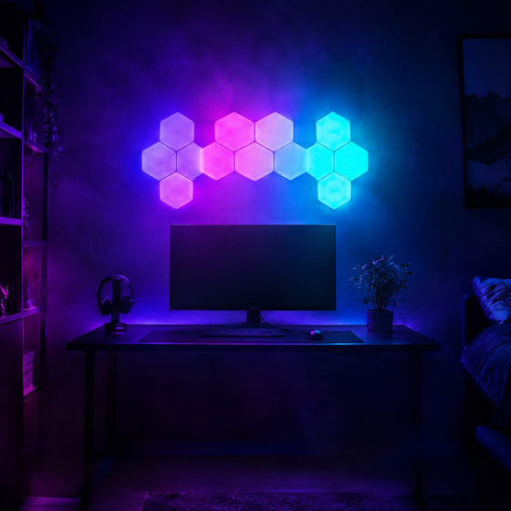 Panneaux LED modulaires hexagonaux en dégradé violet, rose et cyan au-dessus d'un bureau de gamer