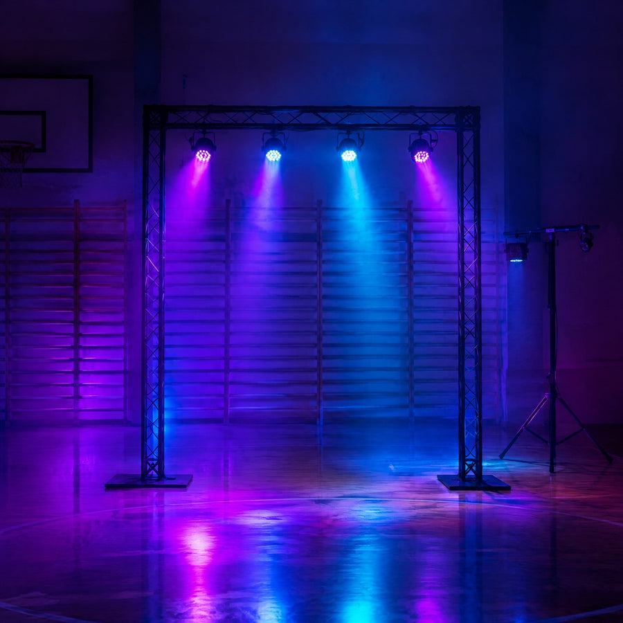 Structure portique en aluminium noir avec projecteurs et pied en T dans un gymnase aménagé pour une fête