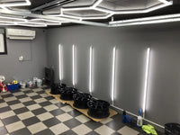 Barres LED murales de détailing – barres verticales au mur et hexagones lumineux au plafond d'un atelier