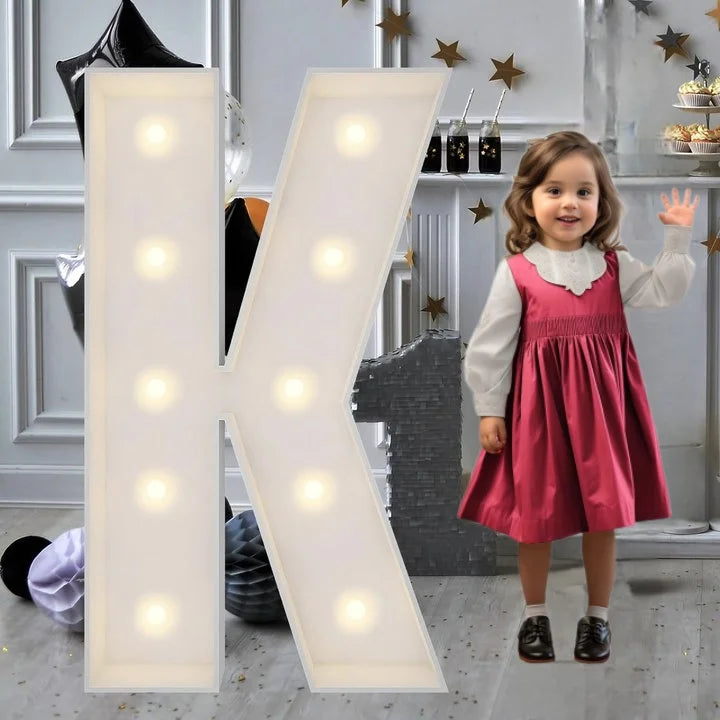Lettre marquee 120 cm – la lettre K allumée à côté d'une petite fille