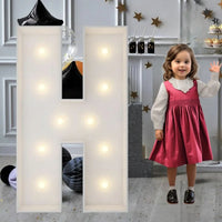 Lettre marquee 120 cm – la lettre H allumée à côté d'une petite fille