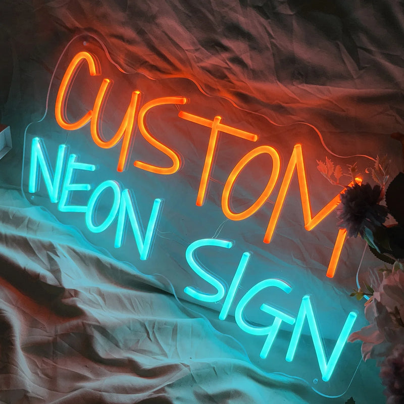 Néon texte personnalisé – lettres orange et bleu glacier posées de biais sur un tissu