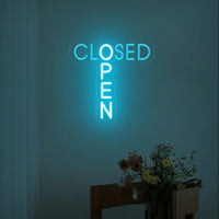 Panneau OPEN CLOSED en néon LED – version bleu turquoise près d'un bouquet de fleurs