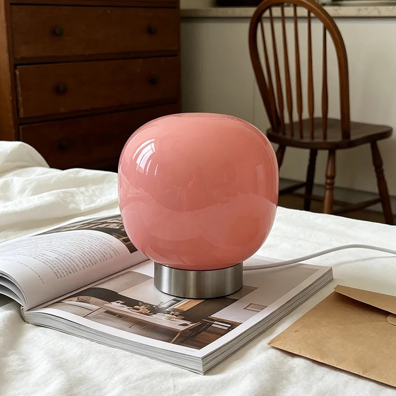 Lampe de table en verre à 3 teintes – lampe rose sur un lit avec un magazine