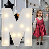 Lettre marquee 120 cm – la lettre M allumée à côté d'une petite fille