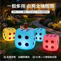 Tabouret lumineux LED en forme de dé – dés lumineux de couleurs différentes dans un jardin, bouteille et verres posés sur un dé