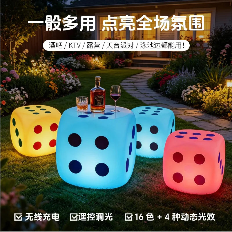 Tabouret lumineux LED en forme de dé – dés lumineux de couleurs différentes dans un jardin, bouteille et verres posés sur un dé