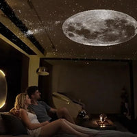 Mini projecteur galaxie à lentille – couple installé sur un canapé sous un ciel étoilé et une Lune projetés