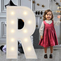 Lettre marquee 120 cm – la lettre R allumée à côté d'une petite fille