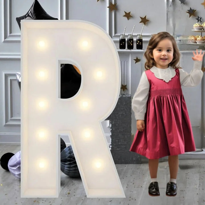 Lettre marquee 120 cm – la lettre R allumée à côté d'une petite fille