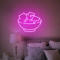 Néon chats et ramen – coloris rose allumé au-dessus d'un lit