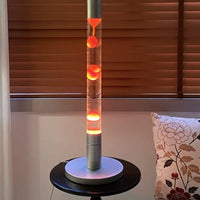 Lampe à lave tube 55 cm – version à cire orange allumée dans un salon