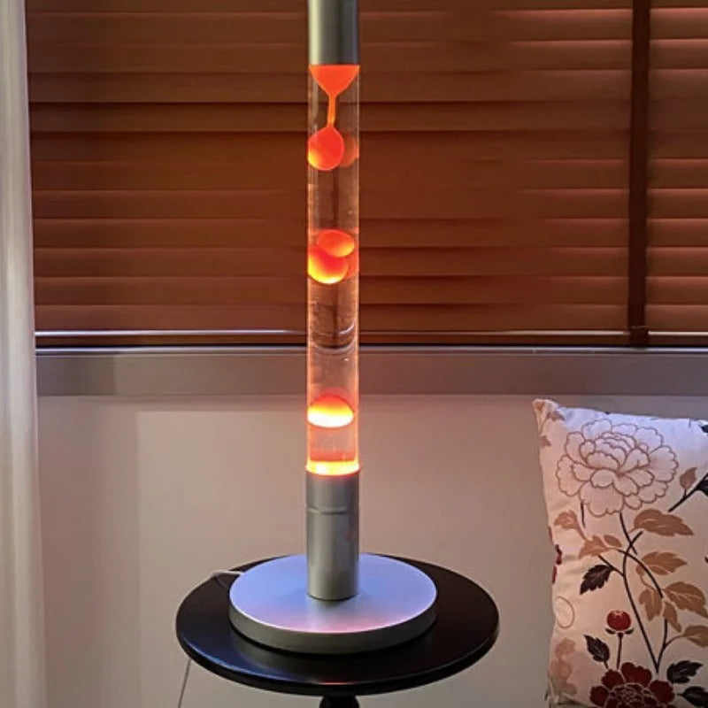 Lampe à lave tube 55 cm – version à cire orange allumée dans un salon