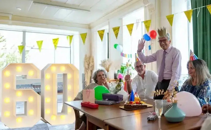 Chiffre lumineux géant – nombre 60 lumineux autour d'une table de fête