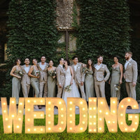 Lettre marquee 120 cm – mot WEDDING allumé devant un mur de feuillage