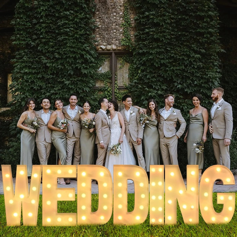 Lettre marquee 120 cm – mot WEDDING allumé devant un mur de feuillage