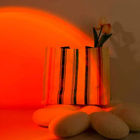 Lampe coucher de soleil sur pied 24 cm – projection orange derrière un sac et des coussins