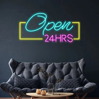 Panneau Open 24HRS en néon LED – ambiance avec canapé gris au-dessus d'une table basse