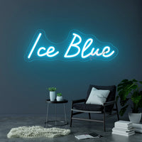 Néon prénom personnalisé cœur ou couronne – texte bleu glacier sur un mur gris au-dessus d'un fauteuil