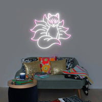 Néon renard kitsune – coloris blanc et rose allumé au-dessus d'un canapé