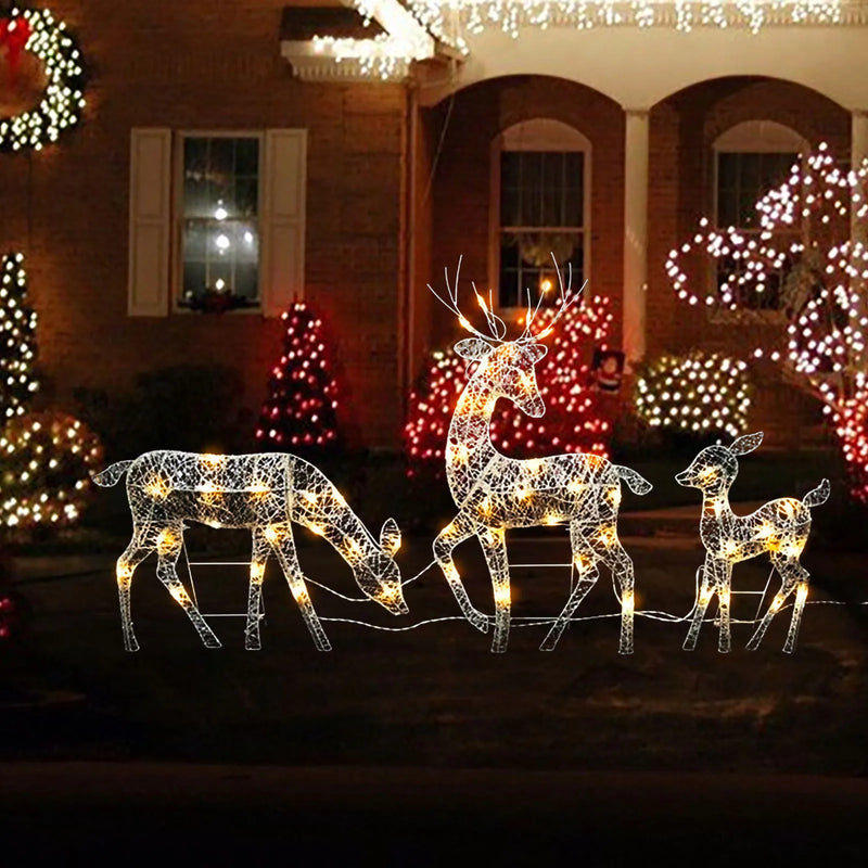 Rennes lumineux Noël – famille de trois rennes éclairée le soir devant une maison