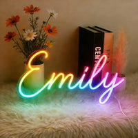 Néon prénom personnalisé RGB multicolore – néon prénom « Emily » posé sur un tapis près de fleurs