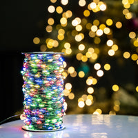 Guirlande fil vert – bobine allumée en multicolore devant un sapin