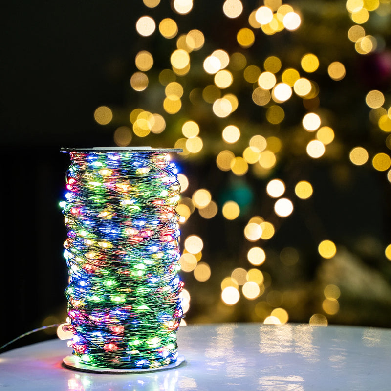 Guirlande fil vert – bobine allumée en multicolore devant un sapin