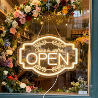Panneau OPEN Come in, we're open – suspendu devant une vitrine fleurie