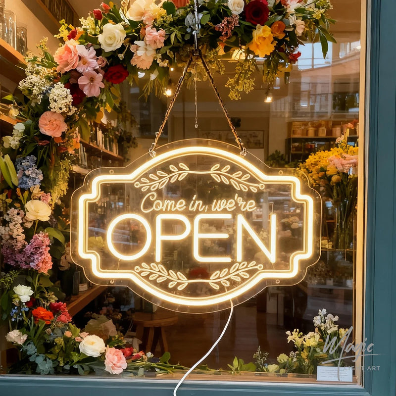 Panneau OPEN Come in, we're open – suspendu devant une vitrine fleurie