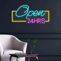 Panneau Open 24HRS en néon LED – ambiance avec fauteuil blanc et plante