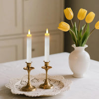 Bougies LED coniques – deux bougies blanches sur chandeliers dorés près de tulipes