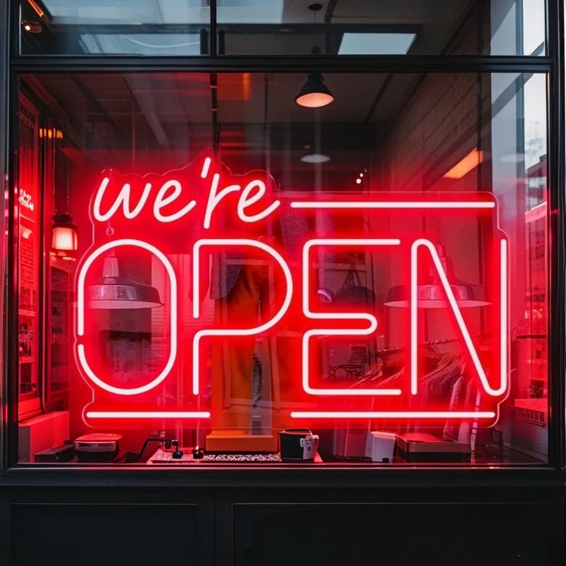 Enseigne néon We're OPEN – version rouge en vitrine d'un magasin de nuit