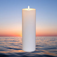 Bougies pilier LED géantes – bougie blanche devant un coucher de soleil sur la mer