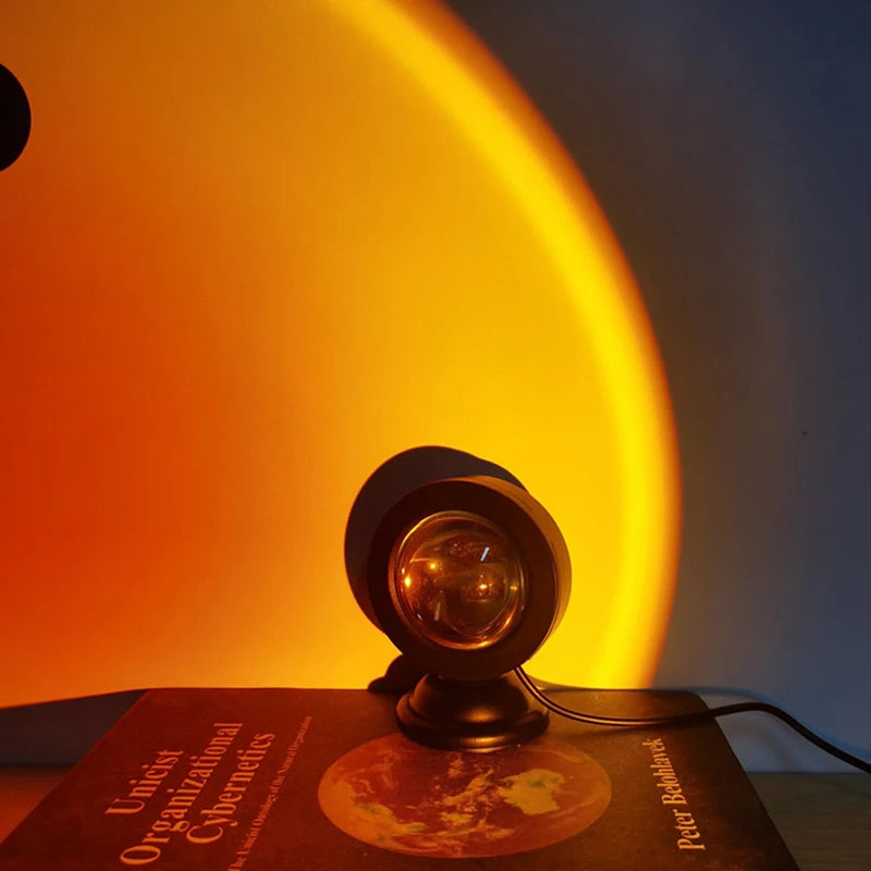 Projecteur coucher de soleil USB – posé sur un livre, halo doré sur le mur