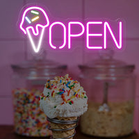 Enseigne néon OPEN cornet de glace – devant un bocal de vermicelles colorés et un cornet de glace