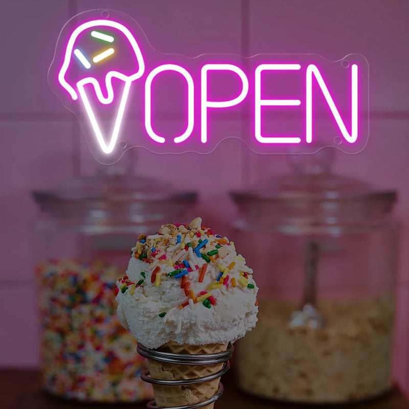 Enseigne néon OPEN cornet de glace – devant un bocal de vermicelles colorés et un cornet de glace