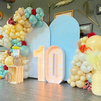 Chiffre lumineux géant 73 cm – nombre 10 allumé devant des arches bleues et des ballons pastel