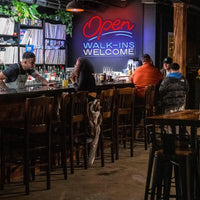 Enseigne néon Open Walk-Ins Welcome – au-dessus d'un bar de nuit