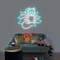 Néon renard kitsune – coloris blanc et turquoise allumé au-dessus d'un canapé