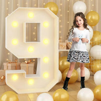 Chiffre lumineux géant – chiffre 9 allumé à côté d'une petite fille