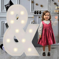 Lettre marquee 120 cm – le symbole & allumé à côté d'une petite fille