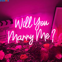 Néon Will You Marry Me – enseigne rose sur un fond de roses et un clap de cinéma