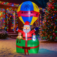 Père Noël gonflable en montgolfière – vue de face devant une maison décorée de lumières